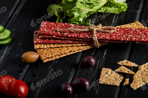 Preview: Beetroot and rye flour crackers with vegetables for making snacks on a black background.