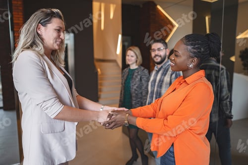 Preview: Two Women Shaking Hands in Front of a Group of People