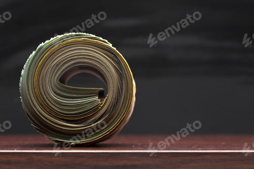 Preview: Rolled stack of paper on a wooden surface with a black background