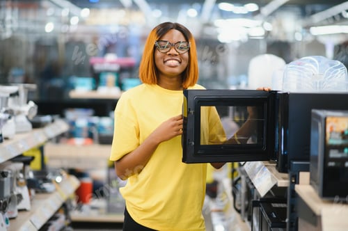Preview: African american woman selected a new microwave oven in hypermarket.