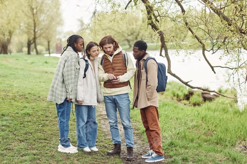 Preview: Group of multiethnic teenagers using digital tablet to find the way during their walk in the park