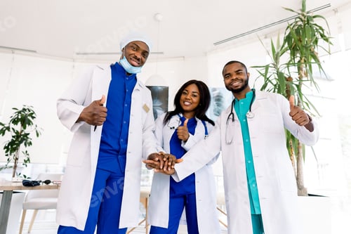 Preview: Doctors team. Health care. Three happy African doctors stack hands together as team for motivation