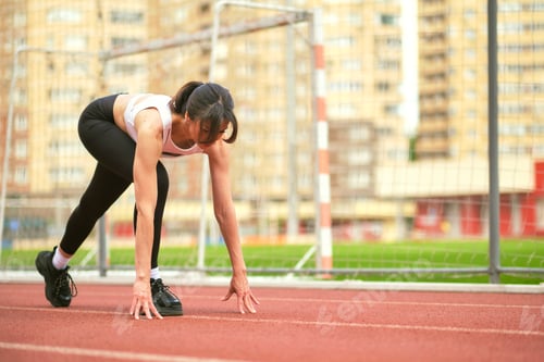Preview: The athletic woman positions herself at the starting line, her focus and readiness evident. This