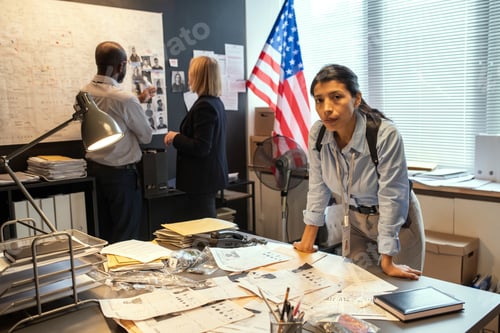 Preview: Young serious Hispanic female detective bending over workplace with documents