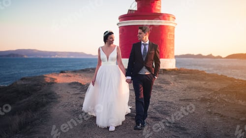 Preview: Just married couple walking against a lighthouse