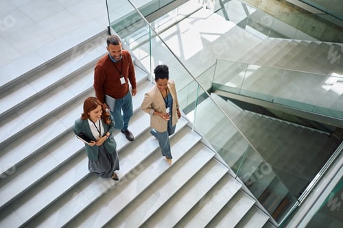 Preview: Above view of happy colleagues walking down the stairs in the office.