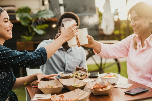 Preview: Happy people eating and cheering at food truck restaurant - Focus on girl hand holding cup of drink