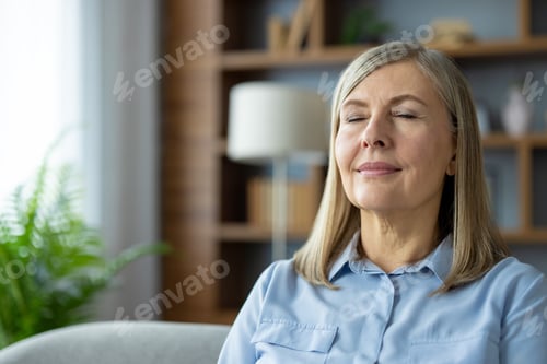 Preview: Mature woman with closed eyes enjoying peaceful moment at home