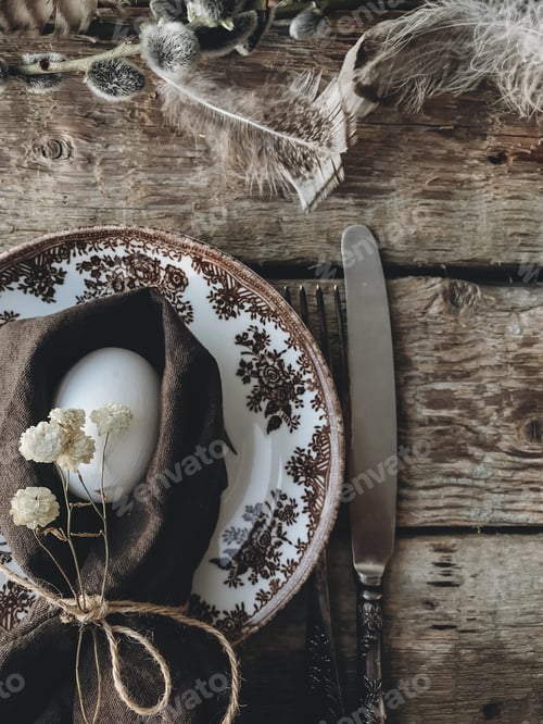 Preview: Stylish rustic Easter table setting. Natural egg, napkin, flowers, vintage plate, cutlery, feathers