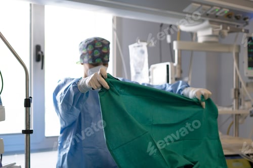 Preview: Surgeon gowning in operating room preparing for surgery