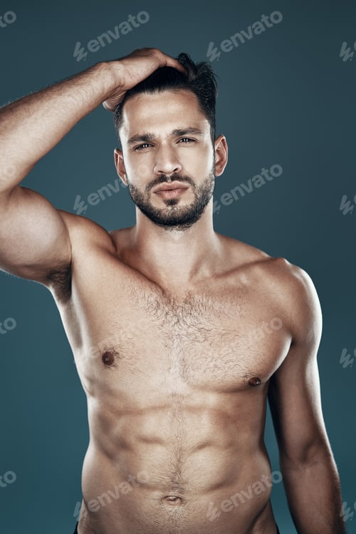 Preview: Handsome young shirtless man looking at camera while standing against grey background