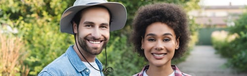 Preview: cheerful multiethnic farmers smiling at camera in blurred garden, banner