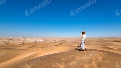 Preview: Lone women traveling in a desert with sand dunes and a clear blue sky in Namibia, Africa