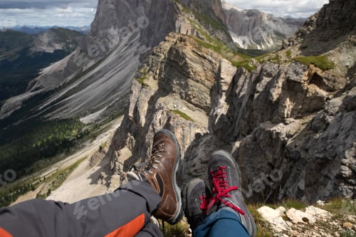Preview: Trekking boots of a hiker couple while sitting on top of a mountain in Seceda, Dolomites, Italy