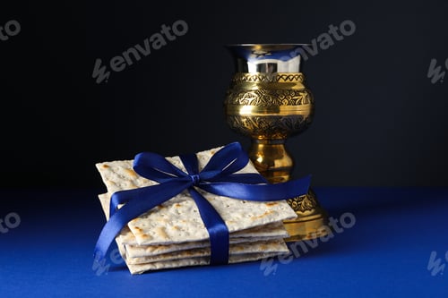Preview: Matzo with ribbon and cup on dark blue background, close up