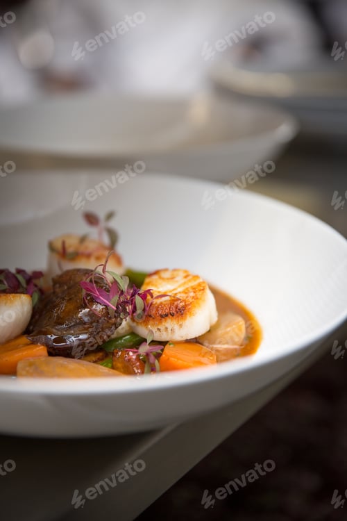 Preview: a fancy fine dining dish bowl sitting on edge of stainless steel counter