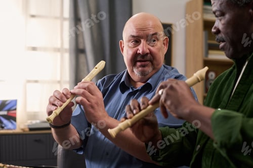 Preview: Middle Aged Caucasian Man Demonstrating Recorder Technique to Senior Black Man