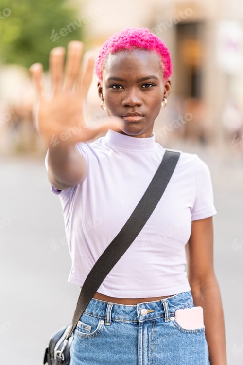 Preview: Vertical photo of a stylish african woman raising the hand to represent stop in the street