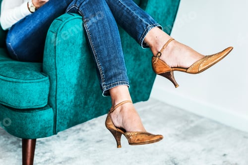 Preview: Closeup pair of feminie legs on the sofa wearing heels