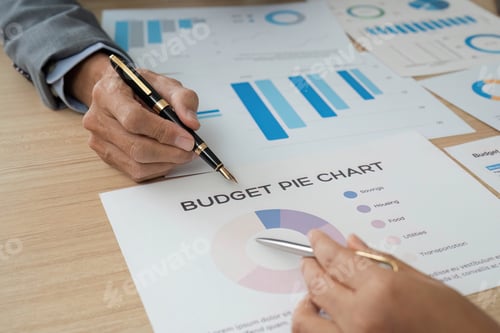 Preview: Close-up of hands reviewing budget pie chart and financial graphs.