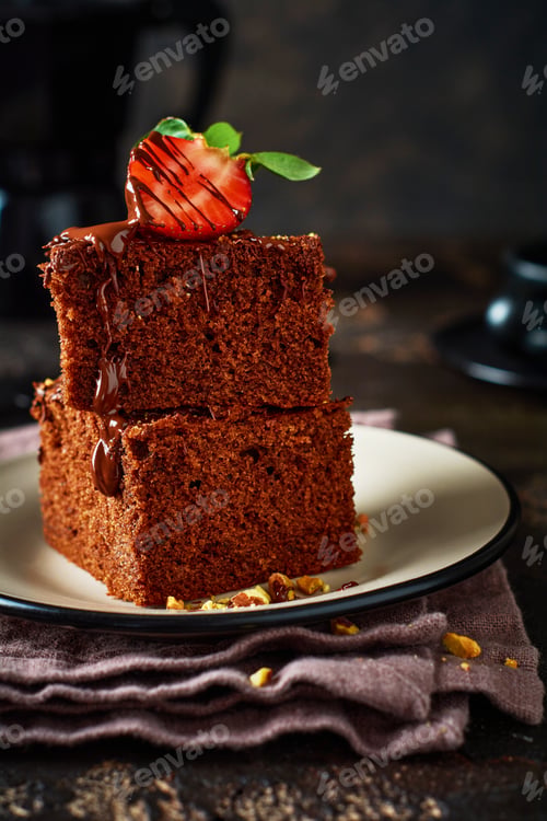 Preview: Stack of pieces or bar of chocolate cake brownie with strawberries and pistachio nuts on the black b