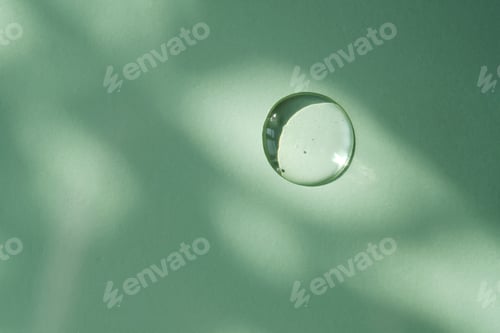 Preview: A drop of micellar water on a green background.