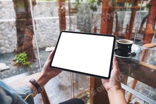 Preview: Mockup image of a woman holding digital tablet with blank white desktop screen in cafe