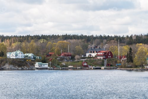 Preview: view from the ship to the rocky coast of Sweden. typical swedish houses on the rocks. cloudy sky