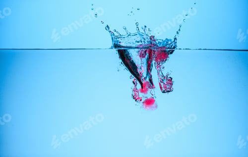 Preview: ice cubes with berries in water with splash, isolated on blue