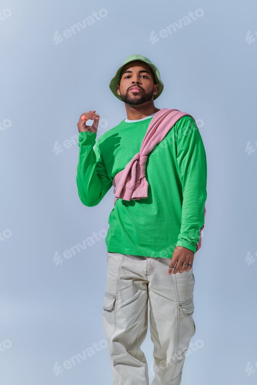 Preview: african american man with raised hand looking at camera on light blue backdrop, fashion concept