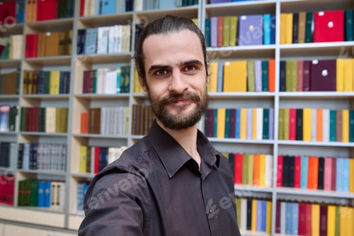 Preview: Headshot portrait of young smiling man posing inside library office
