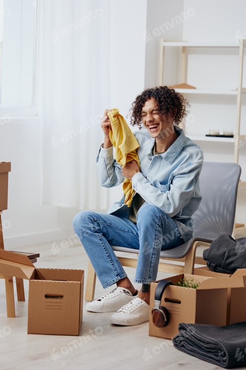 Preview: A young man cardboard boxes in the room unpacking interior