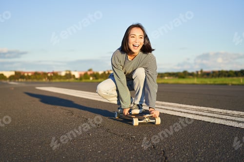 Preview: Portrait of carefree, happy asian girl skating, riding skateboard and laughing, enjoying sunny day