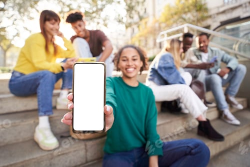 Preview: Smily girl showing smartphone with empty screen at street city with friends Mockup copy space banner