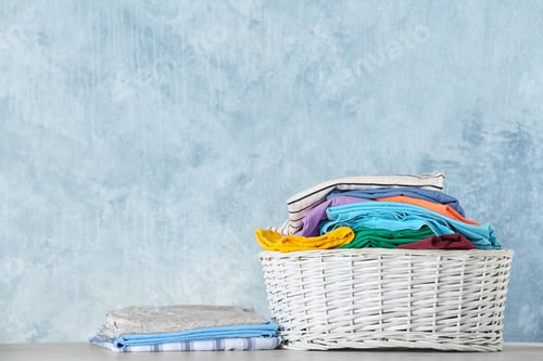 Preview: Basket with clean laundry on table against color background, space for text