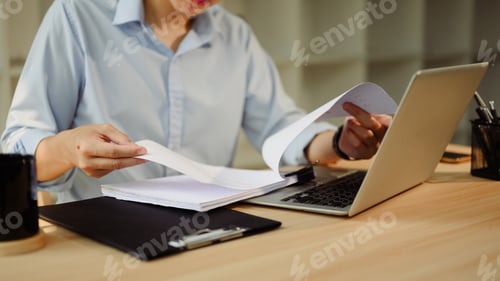 Preview: Focused businessman working with laptop and reviewing documents at workspace