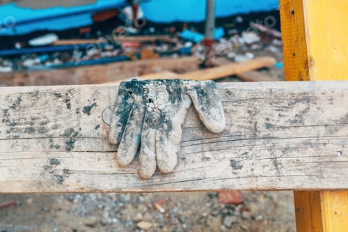 Preview: Old worn protective work glove on construction site