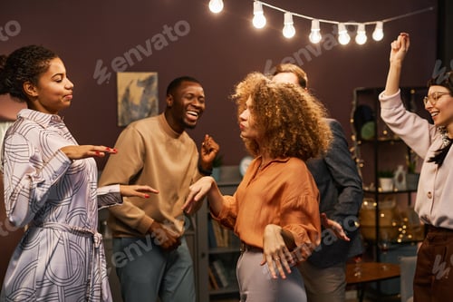 Preview: Group of young intercultural excited friends dancing together at home party