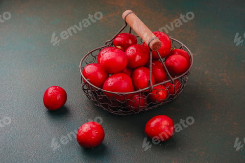 Preview: Red plums in rustic wire basket concept for fresh summer fruit or healthy eating photography