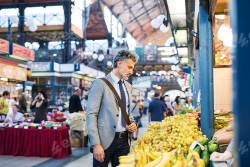 Preview: Mature businessman buying fruit in a city.