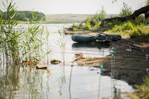 Preview: An inflatable boat, with boxes with fishing tackles, is standing on the water, pond, lake, near the