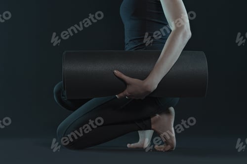 Preview: fit woman with yoga mat practicing yoga on dark black background. copy space