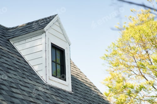 Preview: Gable dormer window on grey shingle roof of cozy house with tree and blue sky