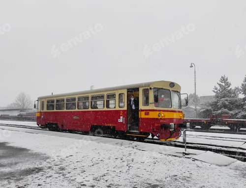 Preview: /NOMINATED/ Red train on the tracks on a snowy day. The driver of the train in a medical mask