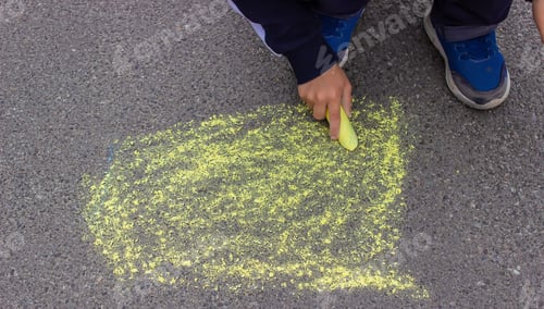 Preview: A small child draws with chalk on the pavement.