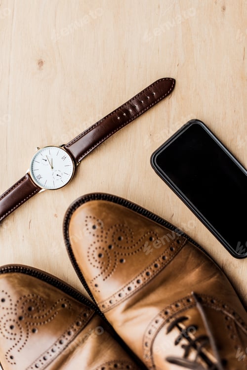 Preview: top view of watch, smartphone and shoes on wooden table