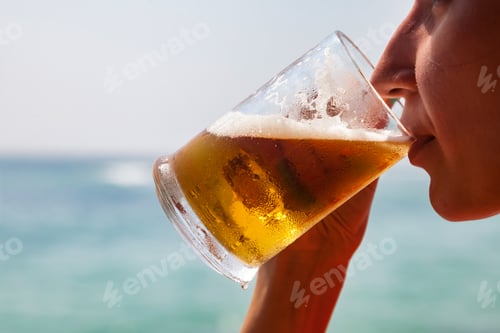 Preview: Closeup of pretty cover lady drinking fresh cool beer at blue sea background