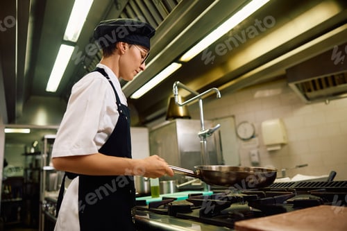 Preview: Female chef cooking in the kitchen at restaurant.