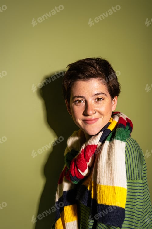 Preview: portrait of carefree woman wearing trendy scarf and smiling at camera on green background with
