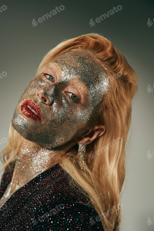 Preview: alluring young woman with green eyes and glitter all over body and face posing on grey backdrop